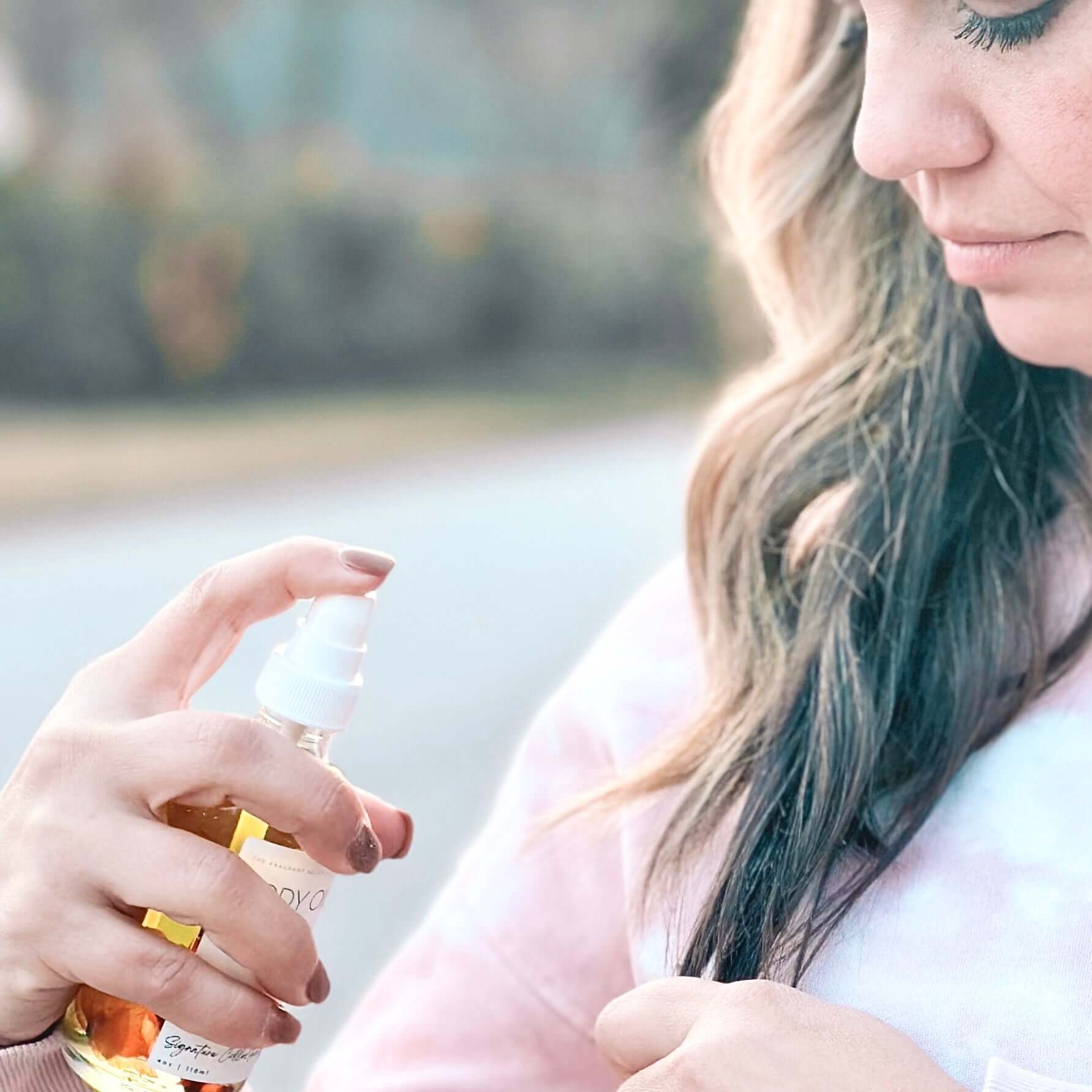 Woman applying our Body Oil Serum to the ends of her hair.