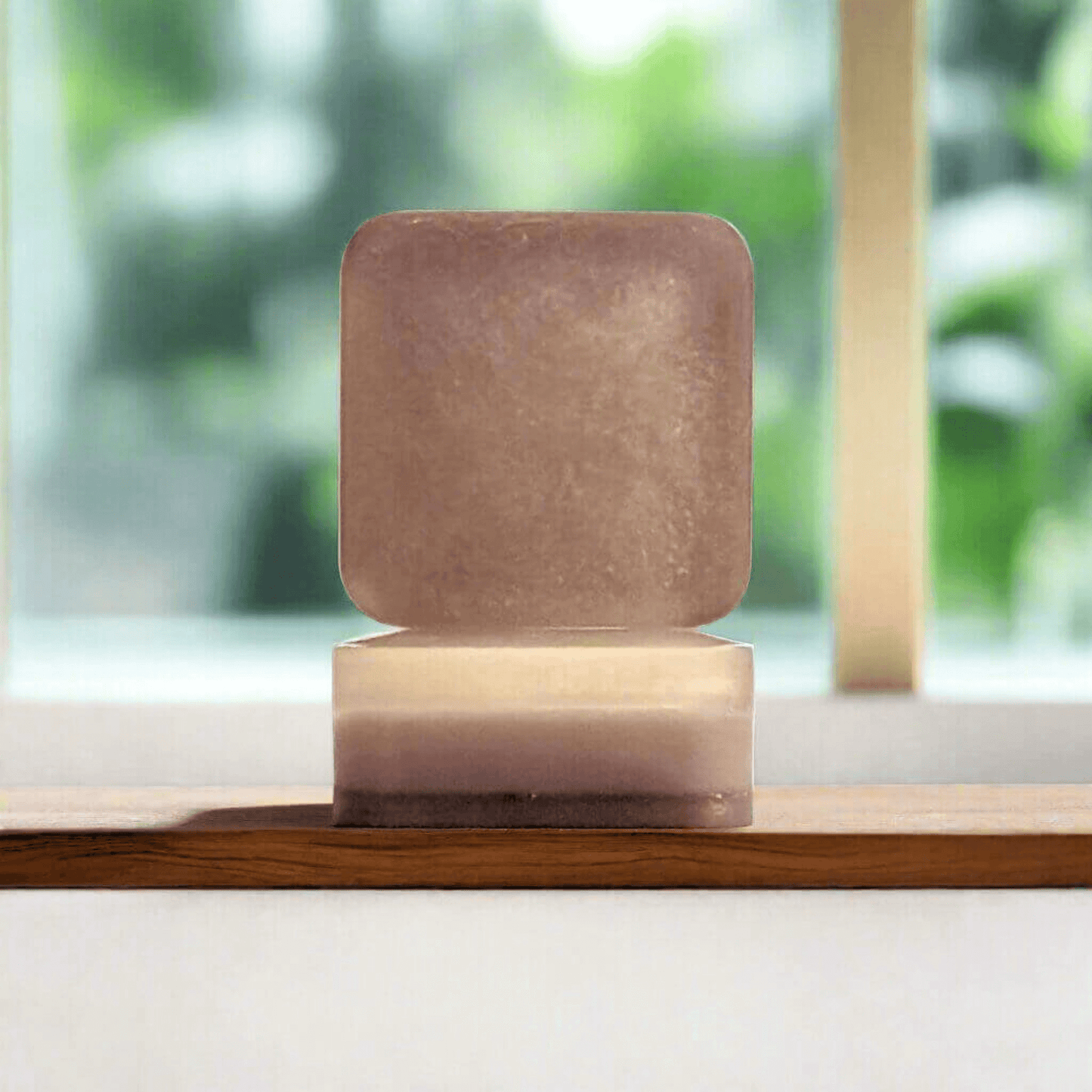 Cashmere Whispers soap in front of a bright bathroom's bright window on a wooden counter.