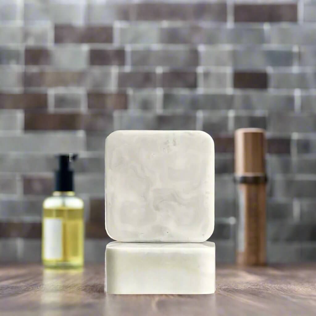 Ode To a Gentleman soap on wooden countertop in front of a grey brick wall, surrounded by men's cologne bottles.