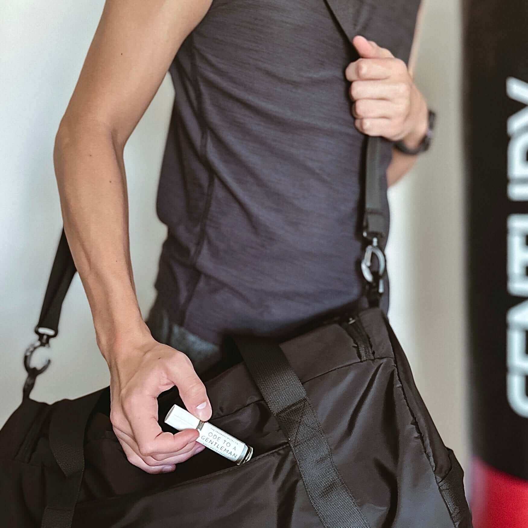 Guy putting his compact-sized Roll-On Fragrance in his gym bag to-go.