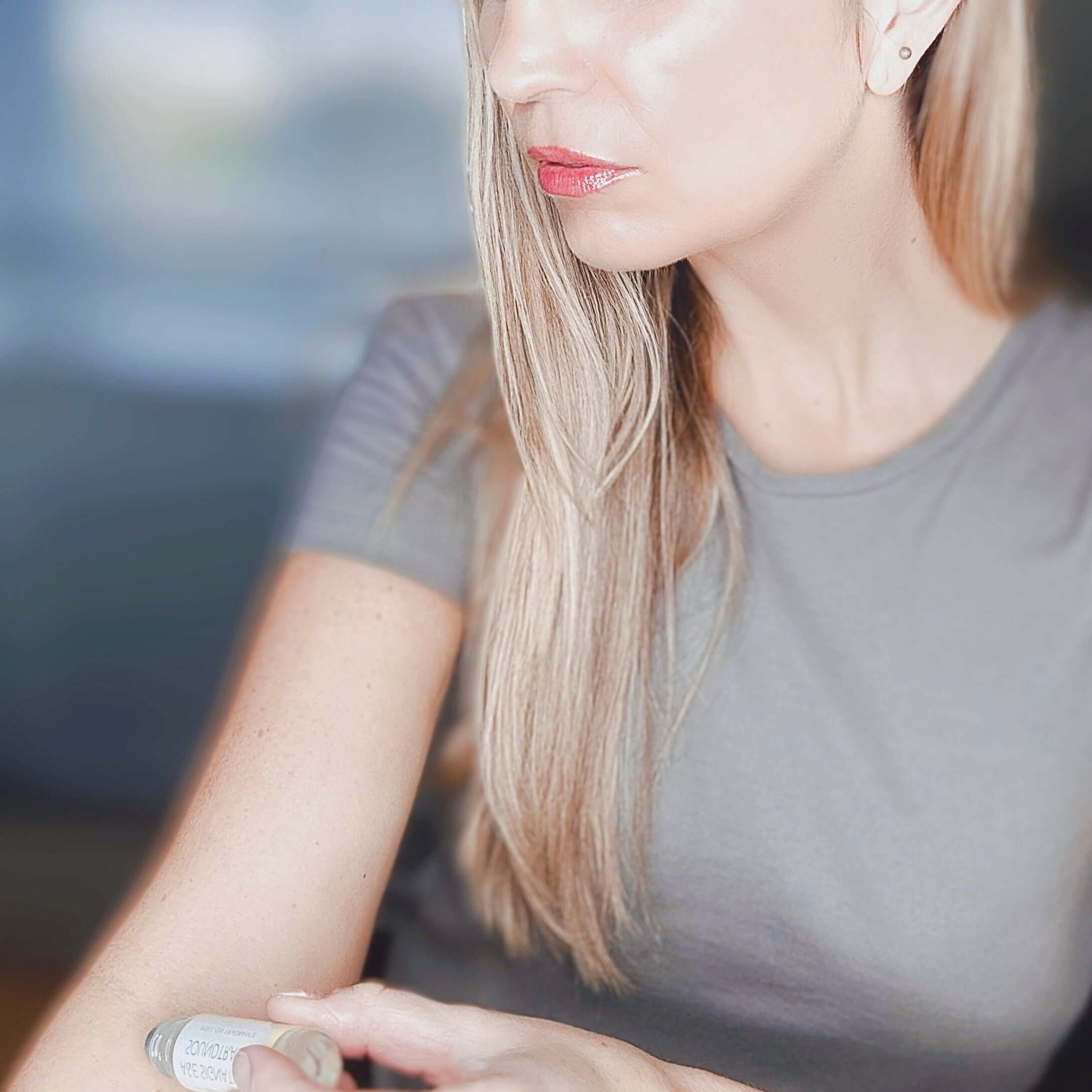 Woman using our Roll-On Fragrance on the inside of her arm.